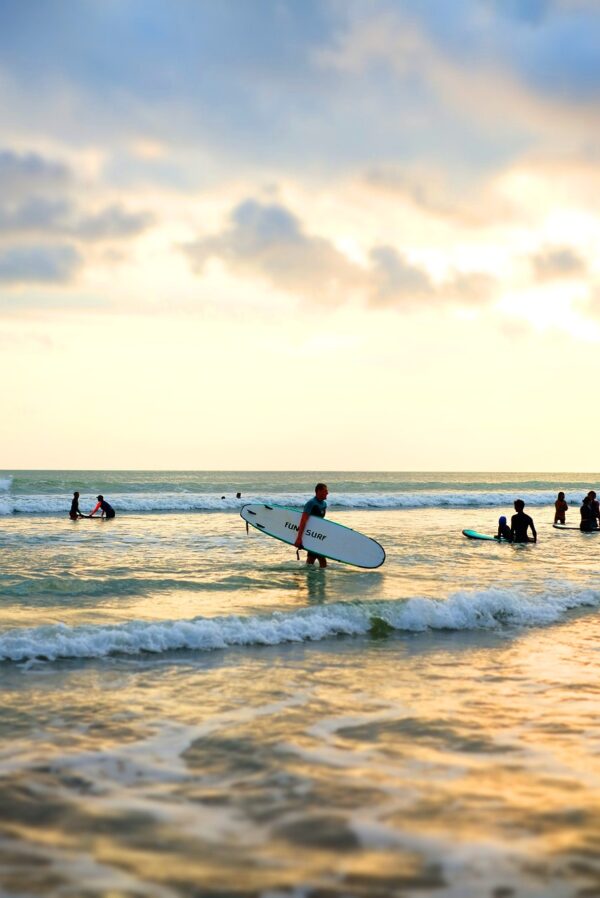 Surfer with a sunset getting out of the water